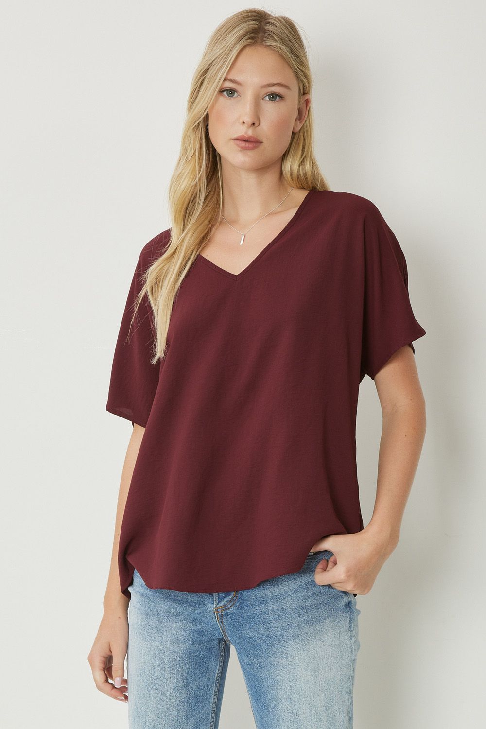 Solid v-neck top featuring asymmetric rounded hem detail. Unlined - 3 Colors